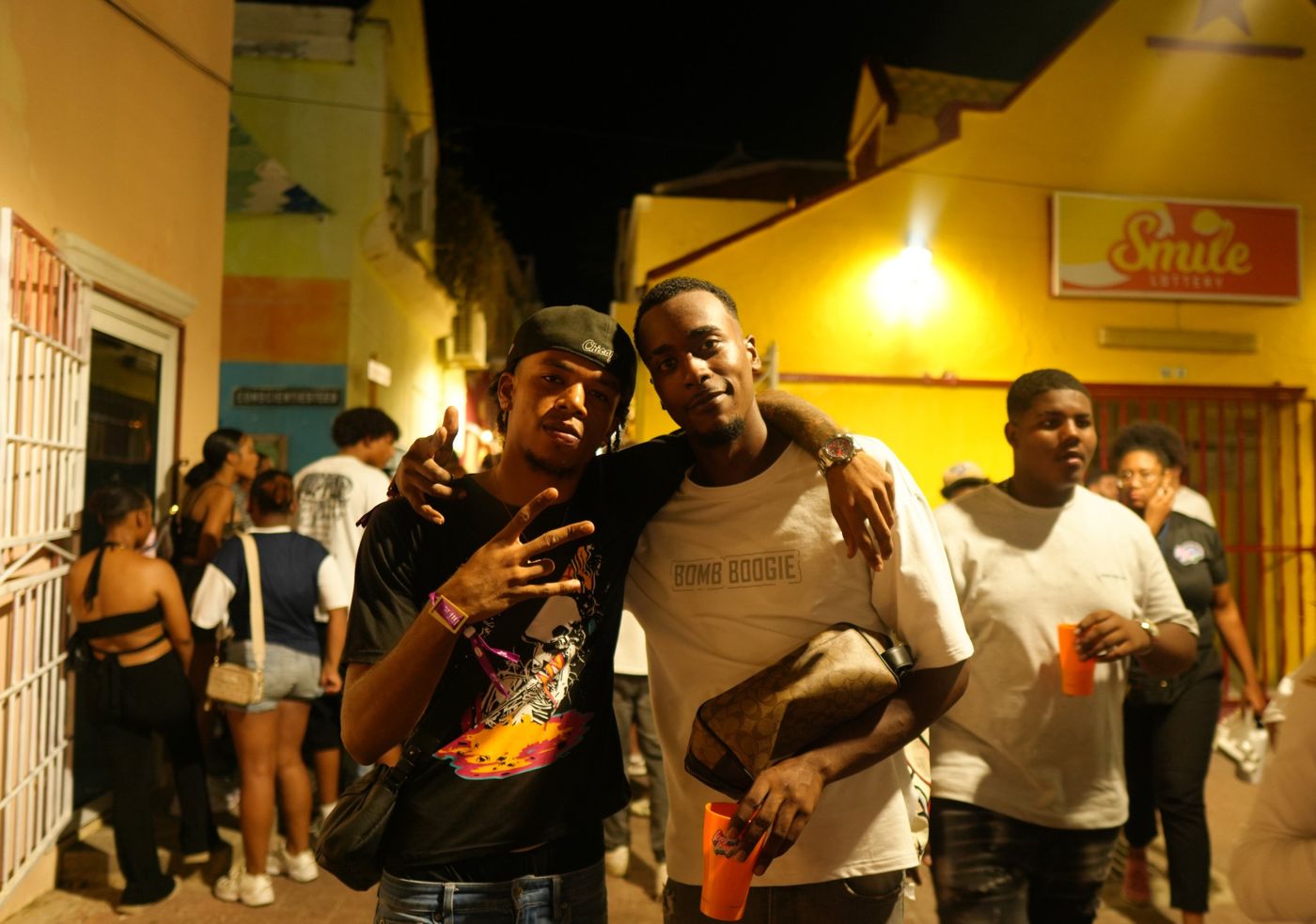 Two friends arm in arm in a yellow-lit alley